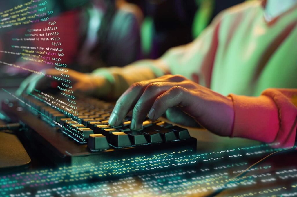 Man's hands on the keyboard next to the program code