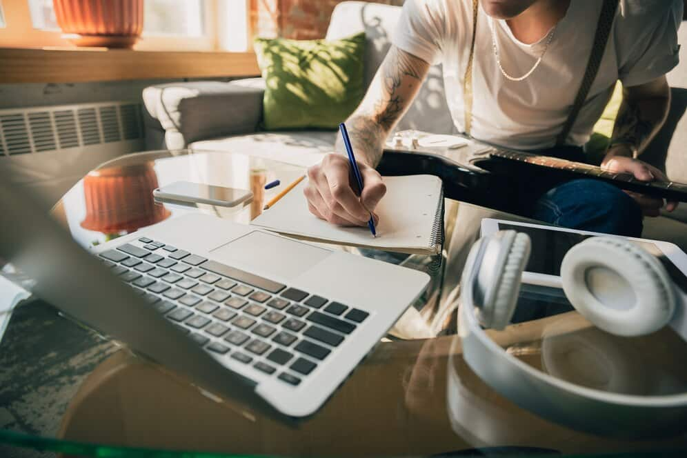 a person writing in a notebook near a laptop